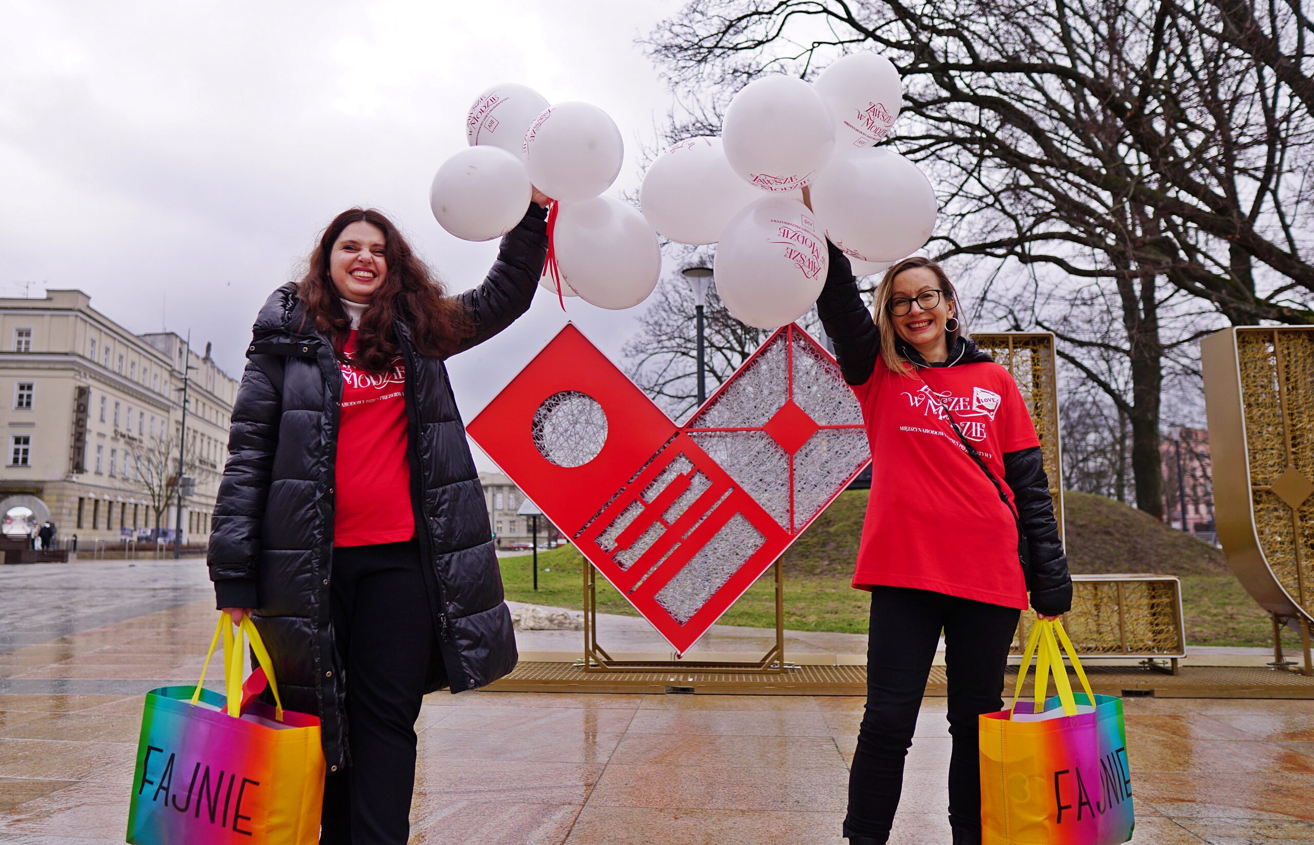 AHF Poland staff conducting a community outreach campaign in a public square, holding awareness materials and balloons promoting condom use and sexual health education.