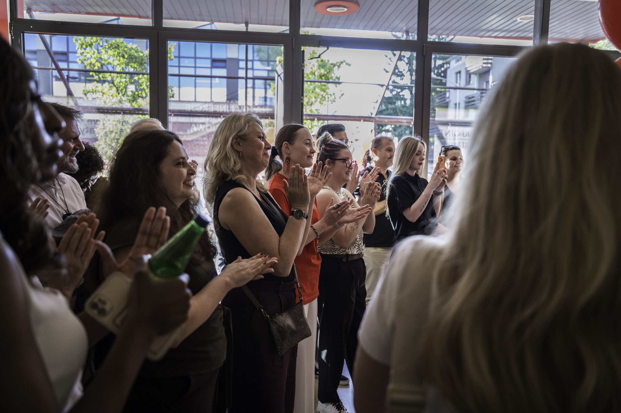 People gathered inside AHF Checkpoint Lublin during a community event, standing together in the testing center and listening to a presentation.