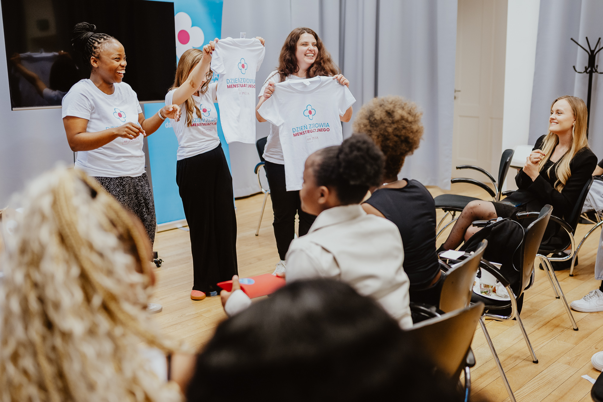 Participants at a community workshop marking Menstrual Health Day, presenting educational campaign materials and engaging attendees in a discussion about menstrual health and health equity.